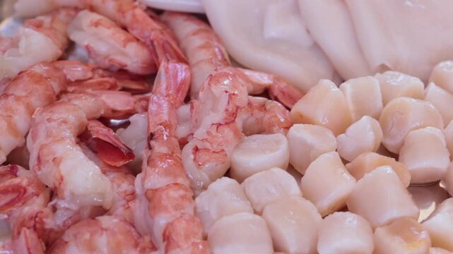 Scallops without shells, shrimp and squid on a plate, cooking seafood
