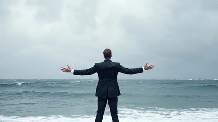 Ocean's Embrace: A businessman stands on a windswept beach, arms outstretched, gazing out at a turbulent ocean, symbolizing resilience and facing challenges head-on.