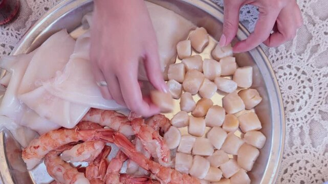 Scallops without shells, shrimp and squid on a plate, cooking seafood