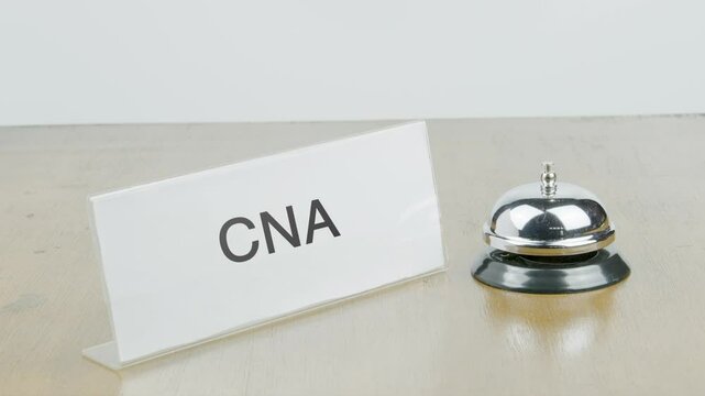CNA Office or Room with Hand Ringing The Bell on Desk or Table Multiple Times.