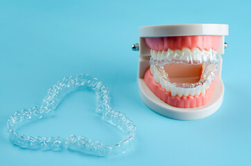 Close-up. Transparent aligners for artificial jaw teeth on a blue background