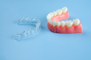 Invisible dental teeth brackets tooth aligners on blue background. Plastic braces dentistry retainers to straighten teeth