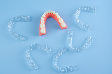 Close-up. Transparent aligners for artificial jaw teeth on a blue background