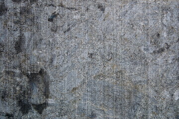 Texture of rough gray concrete wall showing scratches and marks from wear over time in an urban setting