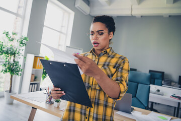 Photo of pretty young girl confused amazed read report scared wear yellow plaid shirt coworking...