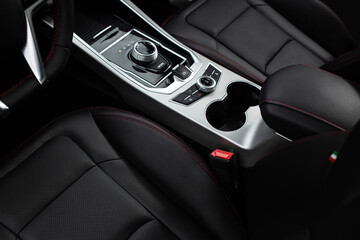 A black leather car seat with a silver cup holder