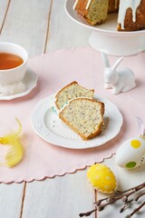 Sliced ​​easter cake in wreath shape with sugar icing colorful sprinkles on ceramic plate on light wooden background.