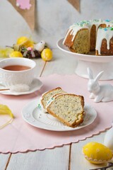 Sliced ​​easter cake in wreath shape with sugar icing colorful sprinkles on ceramic plate on light wooden background.