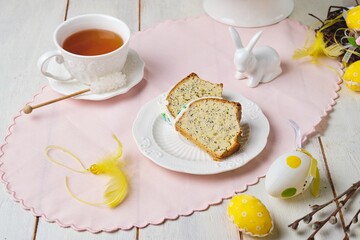 Sliced ​​easter cake in wreath shape with sugar icing colorful sprinkles on ceramic plate on light wooden background.