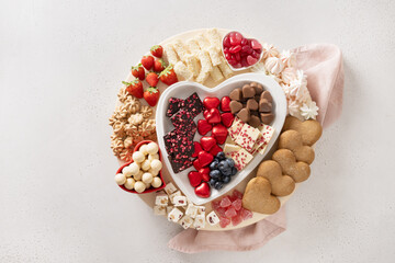 Charcuterie Valentines Day sweet board with chocolate candy, red hearts, cookies, marshmallow, strawberries and candies on white background. Copy space. Top view.