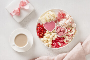 Romantic breakfast with coffee, gift and Valentine's Day charcuterie board with chocolate sweets and strawberries on white background. Tasty dessert or romantic appetizer.