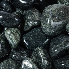 Wet shiny textured round dark stones close up