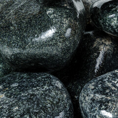 Wet shiny textured round dark stones close up