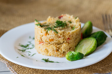 homemade cooked bulgur with Brussel sprouts in a plate, on a wooden table