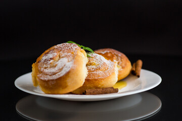 Baked goods. Sweet buns with cottage cheese filling and honey in a plate isolated on a black background
