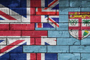 colourful painted big flag of great britain and flag of Fiji on a massive old brick wall background. concept