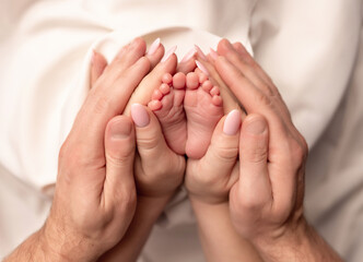 Children's feet in the arms of their parents. On a white background.