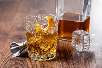 Old fashioned cocktail garnished with orange on wooden table