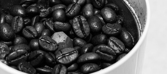 Vue de près sur des grains de café dans un moulin à grains, avec effet noir et blanc
