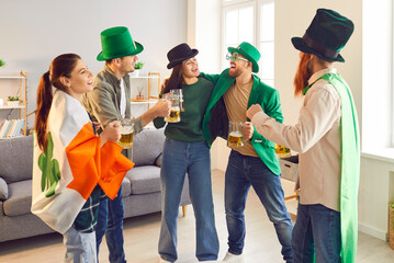 Happy smiling young people friends men and women in green hats standing in circle, talking and...