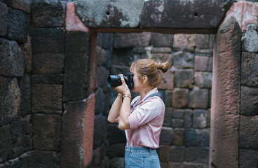  photographer, beautiful Asian female traveler is taking a picture of a Thai temple, visiting a temple during her solo trip. lifestyles, wireless technology, traveling