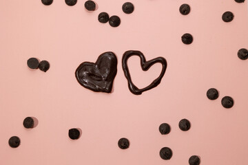 Chocolate filled heart and unfilled heart with sprinkles scattered on a pink background. Valentine's Day concept