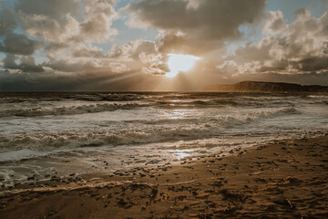 The sun is setting over the ocean, casting a warm glow on the water