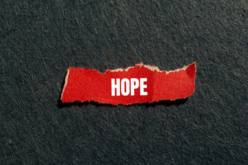 Hope message written on ripped torn red paper piece with gray background. Conceptual hope symbol....