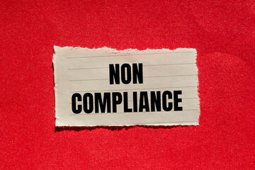 Non compliance message written on ripped torn paper piece with red background. Conceptual non...