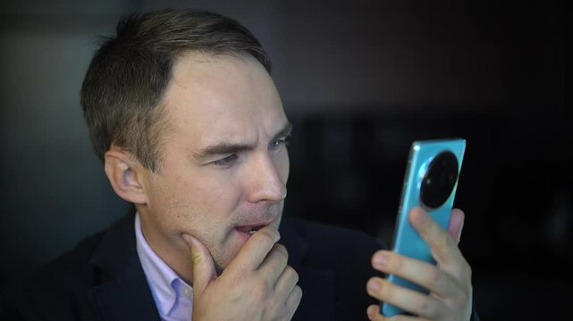 a man reads a questionable message with disbelief on his face. Portrait of brunette man in t-shirt using cellphone, reading news message, mobile application. A suspicious look