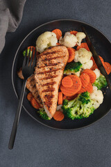 Grilled chicken breast and broccoli, cauliflower and carrots. Chicken meat with vegetables. Healthy food. Dark background top view