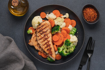Grilled chicken breast and broccoli, cauliflower and carrots. Chicken meat with vegetables. Healthy food. Dark background top view