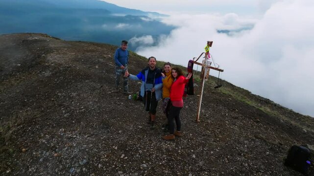 A hiking group of four friends celebrates reaching the top of the Paricutin Volcano caldera in Michoacan, Mexico. A thrilling adventure amidst breathtaking volcanic scenery.