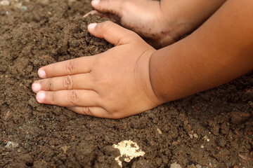 Close up of a little boy's hands playing with dirt or sand. child playing outdoors