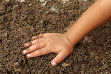 Close up of a little boy's hands playing with dirt or sand. child playing outdoors