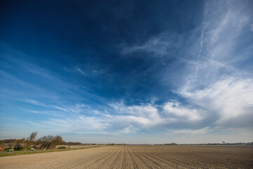 Expansive view of a rural field under a vibrant sky in early spring showcasing the beauty of nature's colors