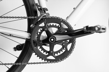 A bicycle chain is shown in black and white. The chain is attached to the pedals and the rear wheel. The chain is in the middle of the bike