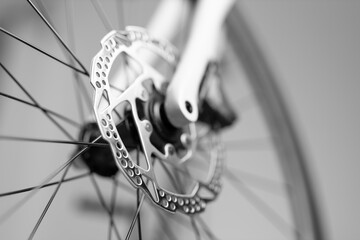 A close up of a bicycle's rear wheel with a shiny silver disc attached to it. The disc is a part of...