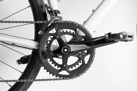 A bicycle chain is shown in black and white. The chain is attached to the pedals and the rear wheel. The chain is in the middle of the bike