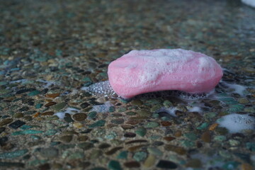 close up photo of wet bar of soap with foam on the floor