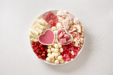Charcuterie Valentines Day sweet board with chocolate candy sweets, red hearts, marshmallow, blueberry, strawberries and candies on white background. Copy space. Top view.