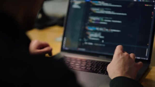 Coding session featuring a programmer working on a laptop in a tech workspace during daytime hours