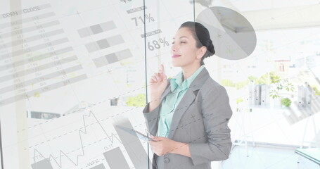 Image of financial data processing over biracial businesswoman using tablet in office