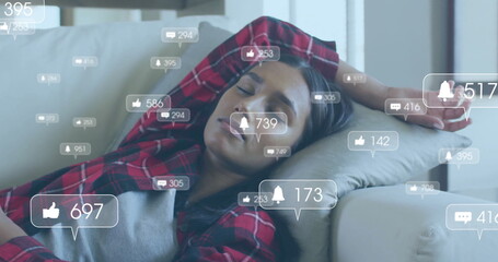 Image of media icons over biracial woman sleeping on couch