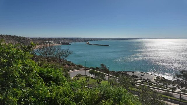 motion lapse video captures the scenic coastal view from "Ras Lafaa" in Safi, Morocco, showcasing the expansive ocean, clear sky, and lush greenery in the foreground