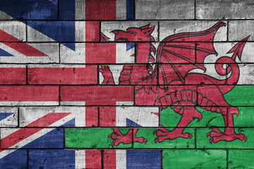 colourful painted big flag of great britain and flag of wales on a massive old brick wall background. concept