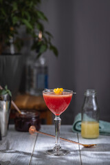 Refreshing red cocktail garnished with lemon peel on bar counter