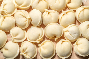 Homemade pelmeni on wooden board close up view. Frozen food for instant preparation 