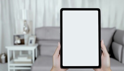 Fototapeta premium Blank tablet screen held by a person on a couch with a blurred background of a living room
