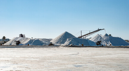 Landscape with desert salt mining factory with piles of white mineral and industrial equipment. The...
